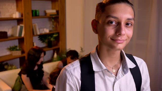 十几岁的阿拉伯男孩的肖像直接看着镜头，带着谦虚的微笑和他的家人在背景上。