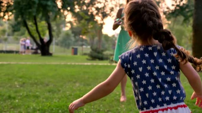 年轻的家庭夏天在公园散步，女儿在抓泡泡，童年的概念