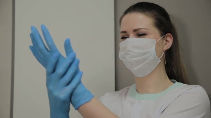 自信的专业女医生戴着口罩和帽子在病房戴上蓝色医用手套。工作中的女医生。医疗保健概念。实验室员工
