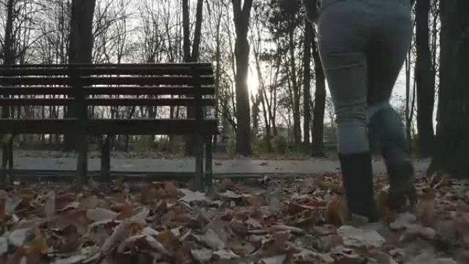 年轻女子秋天在公园里散步，坐在长凳上