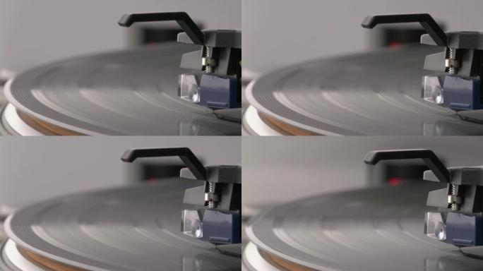 转盘上旋转的黑胶唱片的微距拍摄。线圈盒正在提升乙烯基。背景上的红色频闪灯。