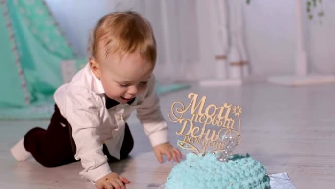 可爱的小帅哥正在玩坐在地板上的第一个蛋糕。
