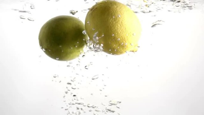 柠檬和石灰在清水中缓慢下落