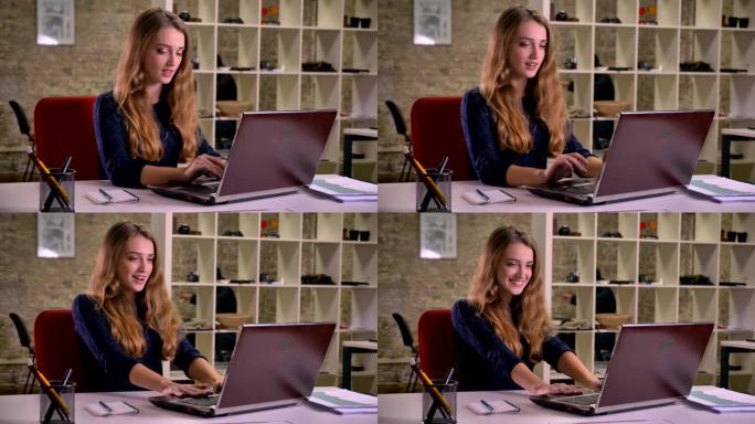 金发碧眼的白人女商人在办公室里用笔记本电脑专心工作的肖像深深地呼气以表达喜悦。