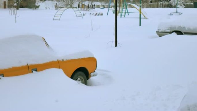 汽车被雪覆盖，在严冬风暴下。雪下院子里的汽车。