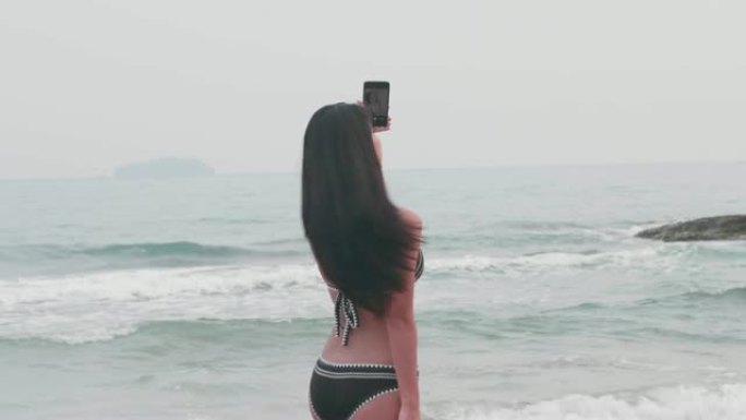 女人在沙滩上使用手机自拍