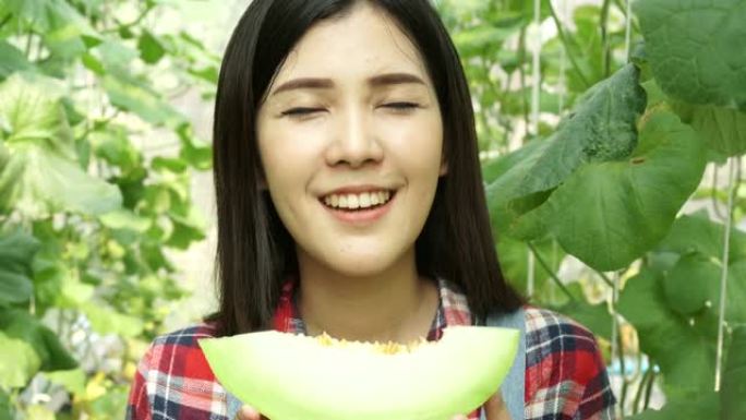 年轻美丽的亚洲女性水果蔬菜乡村农民吃了一片甜瓜，在西瓜农场里闻到了味道