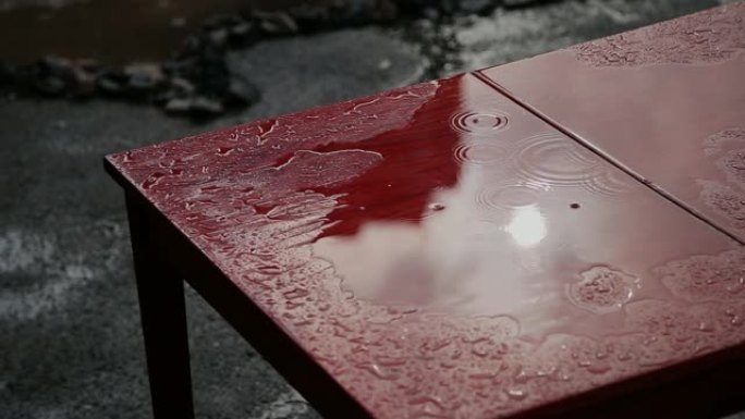 雨水滴在红色的旧桌子上