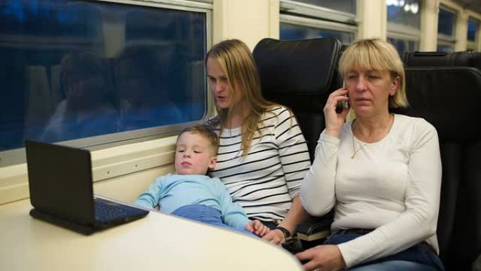 儿子和母亲在笔记本电脑上看视频，奶奶在打电话