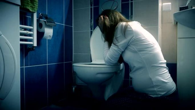 年轻女子在浴室厕所呕吐-怀孕期间晨吐