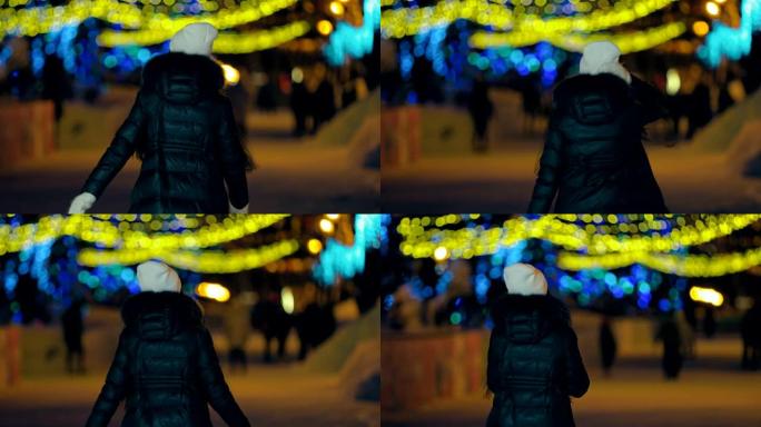 女孩冬天在公园散步。小巷装饰着灯光。后视摄像头。