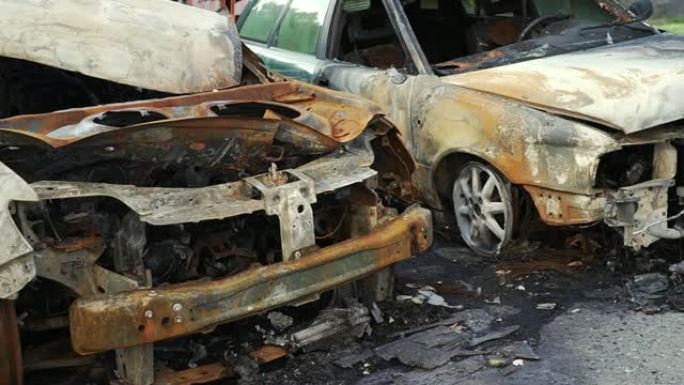 两辆乘用车的滑行慢动作被烧毁，在大城市的一条街道上的一个城市停车场发生了猛烈的火灾。损坏的车辆表面。