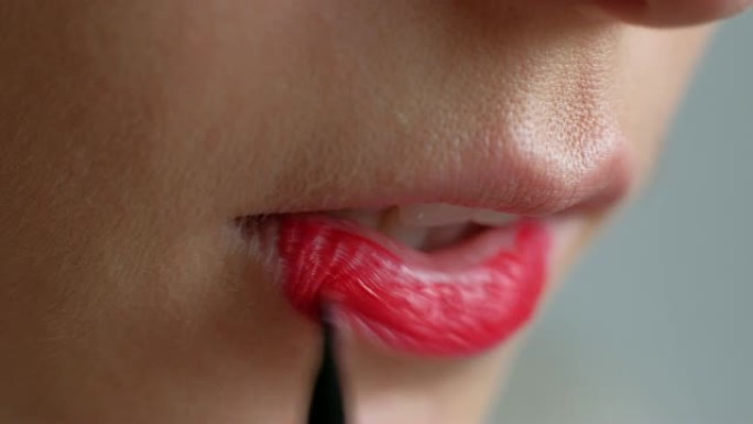 这个女孩在嘴唇上化妆。在嘴唇上涂红色唇膏。特写
