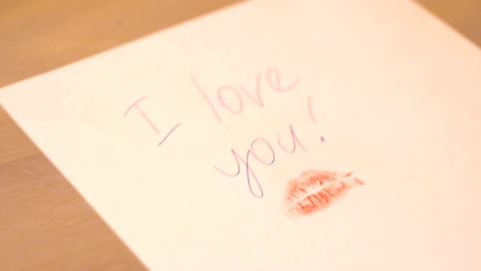 在桌子上放一张纸，上面写着 “我爱你” 和唇印