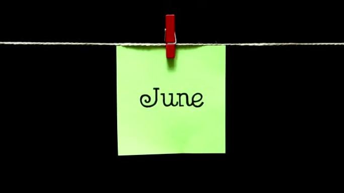 一年中的一个月。夏。在6月的铭文上。用绳子上的衣夹手动连接床单。黑色背景。