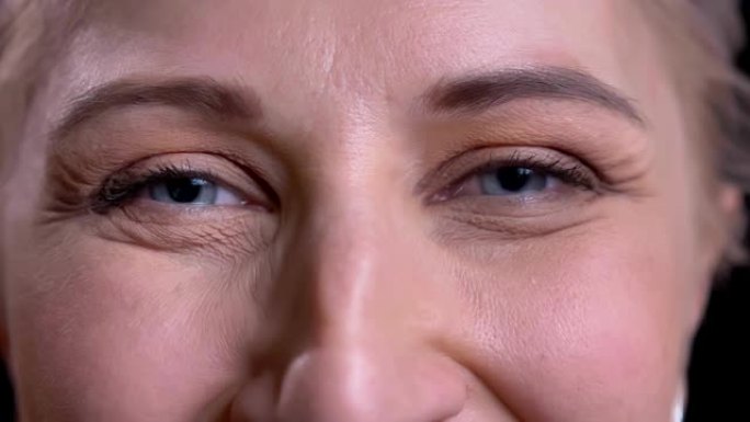 美丽的中年女性灰色眼睛的特写肖像，带着微笑的面部表情看着相机。