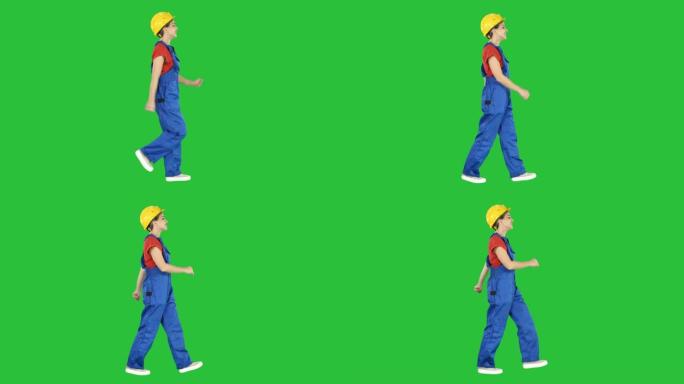 快乐的女人建筑工人以有趣的方式行走，愿意在绿色屏幕上工作，色度键