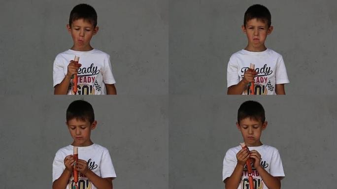 男孩吃香肠，看着灰色背景上的相机