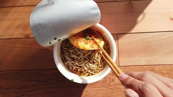 POV: 午餐时间用筷子搅拌方便面 (荞麦面) 和tenpura。日本饮食和文化。POV: 午餐时间