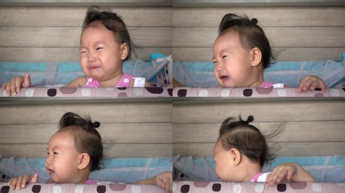 亚洲女婴在婴儿床上哭泣。慢动作