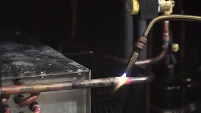 将铜管与焊料熔合在一起的吹炬特写。夹。一名男子焊接管道的特写镜头