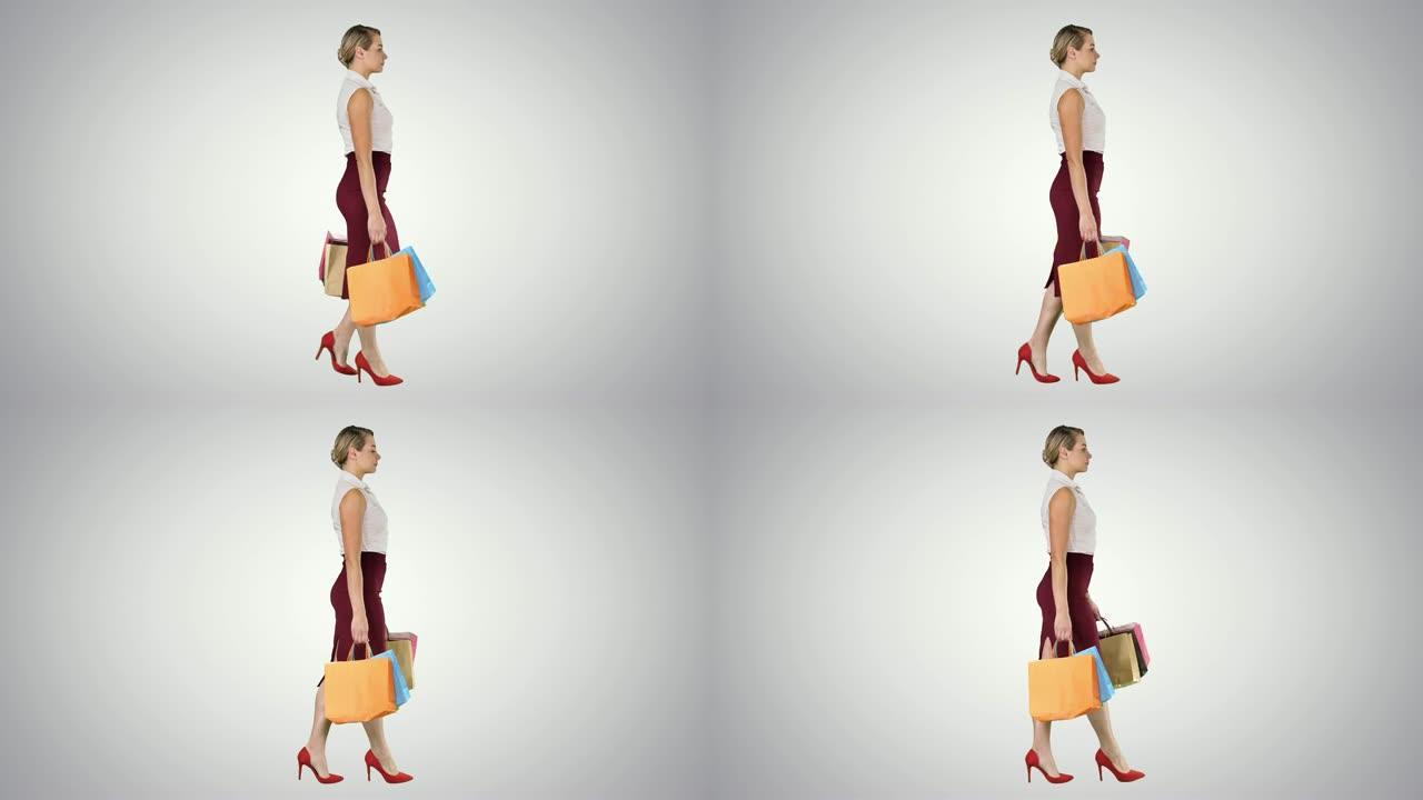 快乐的全长女人每只手拿着纸购物袋，在渐变背景上行走