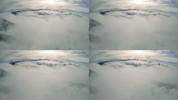 天国滚滚的雾云在积雪覆盖的山谷中的高峰以下