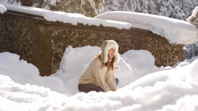 穿着针织毛衣和皮草帽子的快乐女人享受着一个阳光明媚的寒冷早晨，扔雪，在闪闪发光的雪花中旋转。