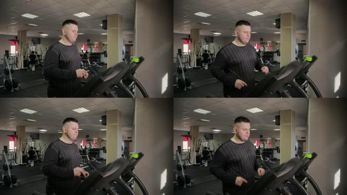 胖子在健身房的跑步机上锻炼
