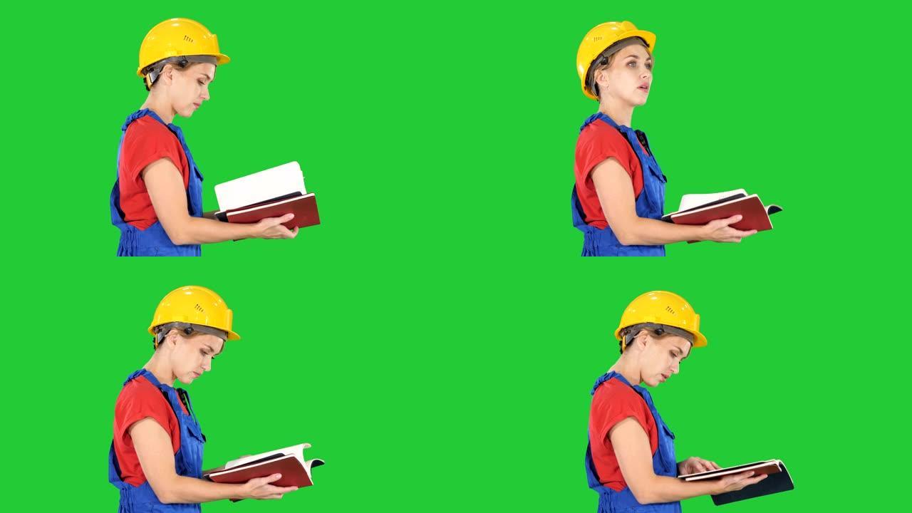 女建筑工人戴安全帽和工作服检查绿色屏幕上的名单，色度钥匙