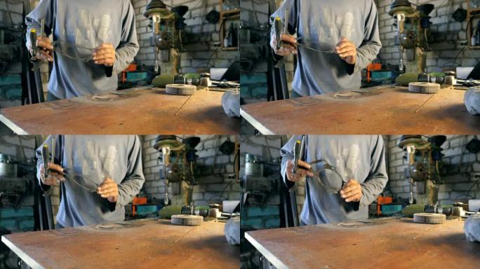 在工作过程中，机械师的手握着细节。男性修理工在车库或车间操作后检查细节。成年男子在修理厂工作。慢动作