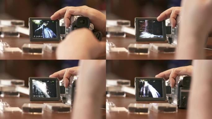 男子在数字迷你数码摄像机的液晶显示屏上观看家庭家庭视频