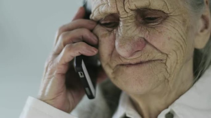 在办公室里，一个有着深深的皱纹的老妇人在用手机说话的特写脸。