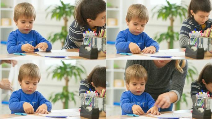 小男孩坐在桌子旁，将他的图画贴在桌子表面