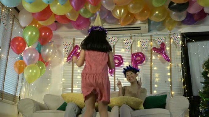 亚洲女儿喜欢在生日聚会上与父亲和母亲一起跳舞。在家庆祝幸福家庭周年。节日和运动反应的概念。4k分辨率