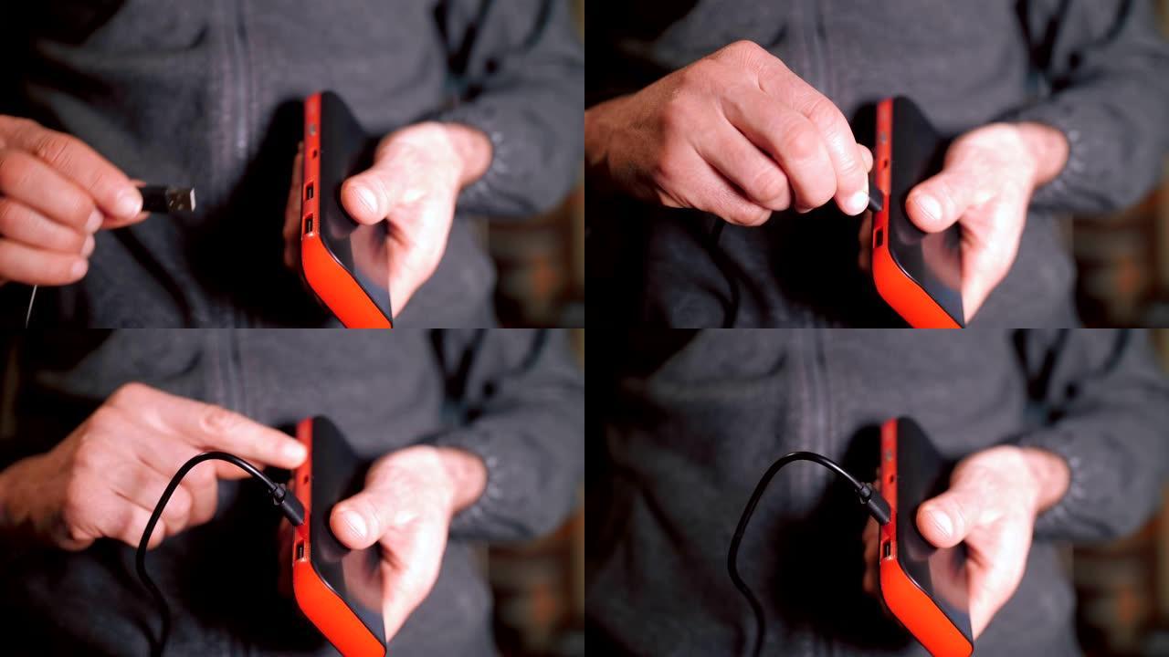 一名男子的手插入USB电缆以连接移动电源和智能手机，为电池充电