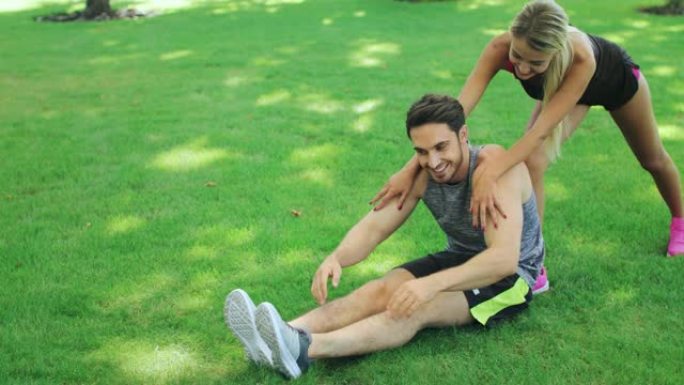 运动女人帮助男友在户外锻炼前热身