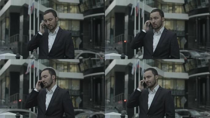 站在办公室外面的俄罗斯商人通过电话接听电话并向商业伙伴解释一些事情
