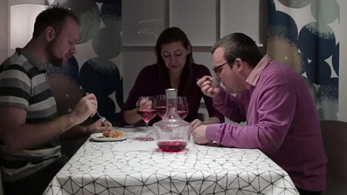 两个男人和女人坐在餐桌旁吃饭和说话
