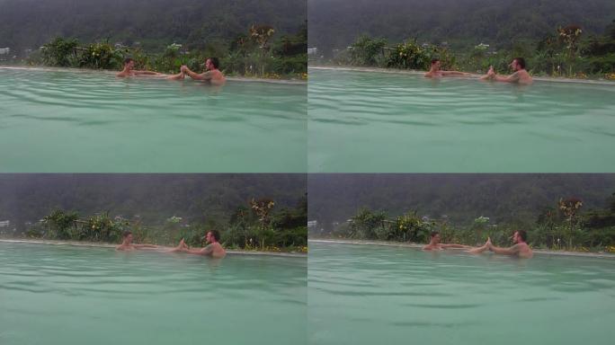 一个男人正在用热硫化氢水在游泳池里做女人的足部按摩