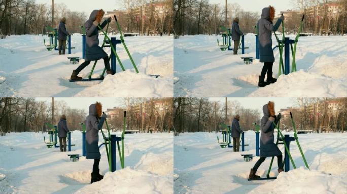 穿着蓝夹克的男人和女人在冬季公园从事模拟器。侧视图。