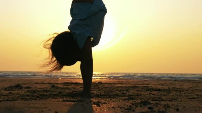 小女孩在海滩上倒立姿势的剪影，特写