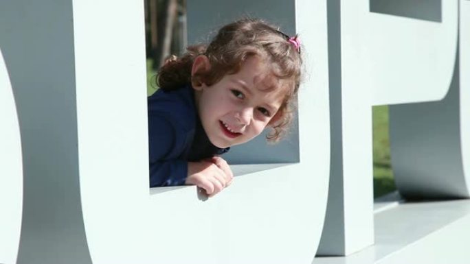 微笑的小女孩看着大塑料字母O