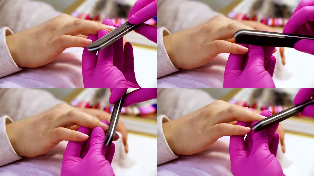 美甲专家向客户抛光指甲。美甲美容师在美甲沙龙给女人做指甲。女人正在修指甲