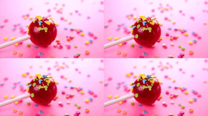 粉色圆形棒棒糖特写粉色背景。小动物形象形式的彩釉散布在红色糖果上。