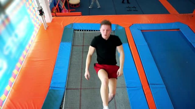 一个年轻人跳上运动蹦床。
