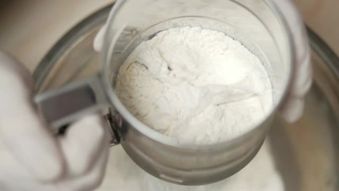 4K-厨师用筛子筛面粉。顶视图