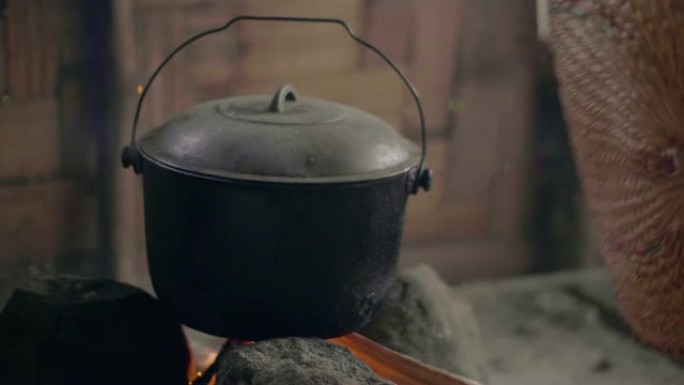 用风扇吹火，在篝火上煮饭。在传统的亚洲村庄的火锅中准备烧柴的晚餐。