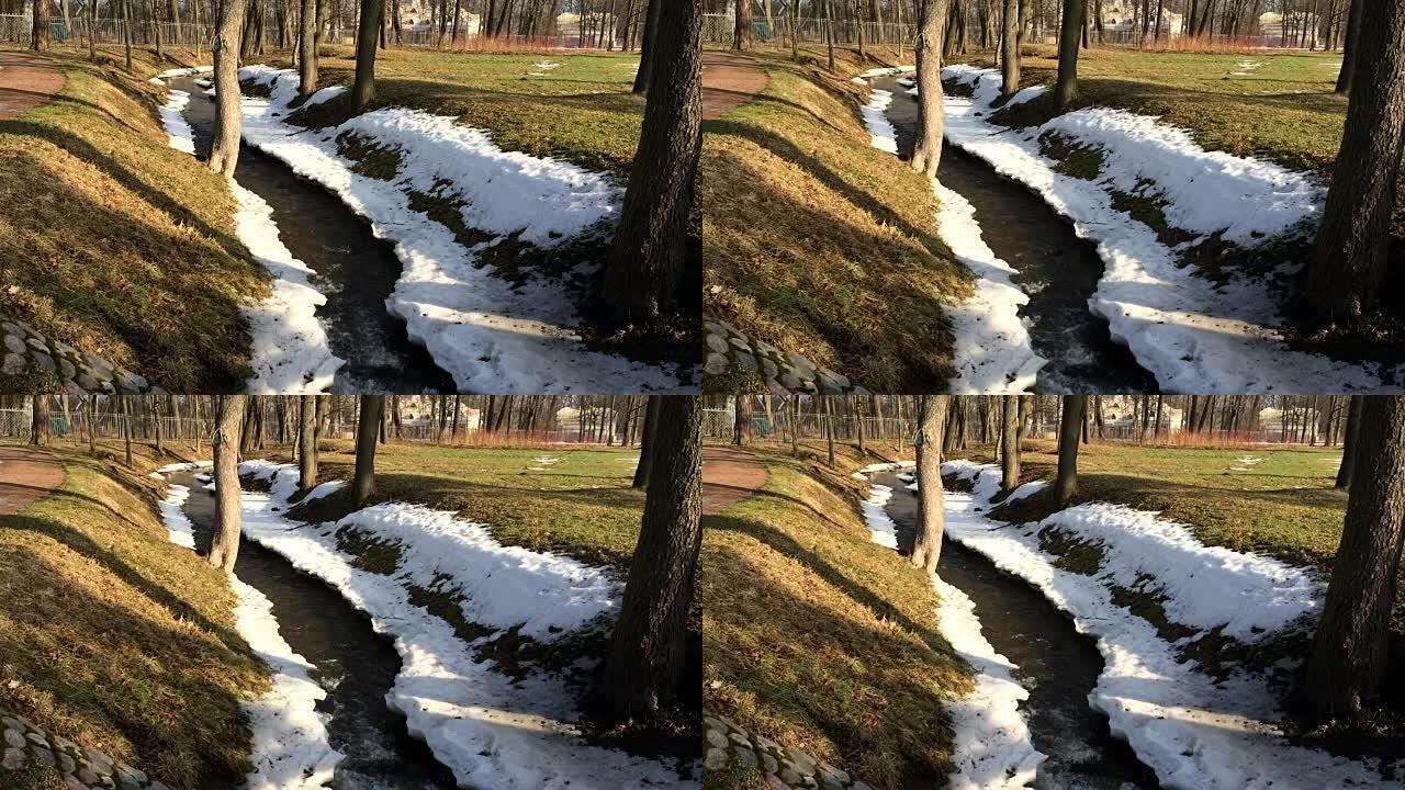春天公园的溪流在融化的积雪中流动