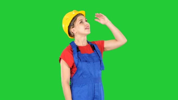 工程师建筑工人的女人抬头看着惊人的东西，在绿色屏幕上大笑，色度键